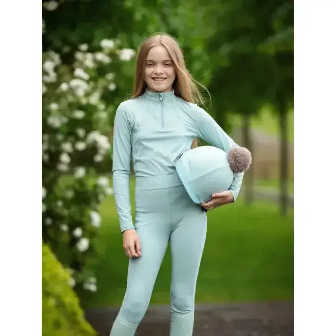 Light blue lemieux young rider helmet with a fuzzy brown pom pom for young rider base layer aqua outfits