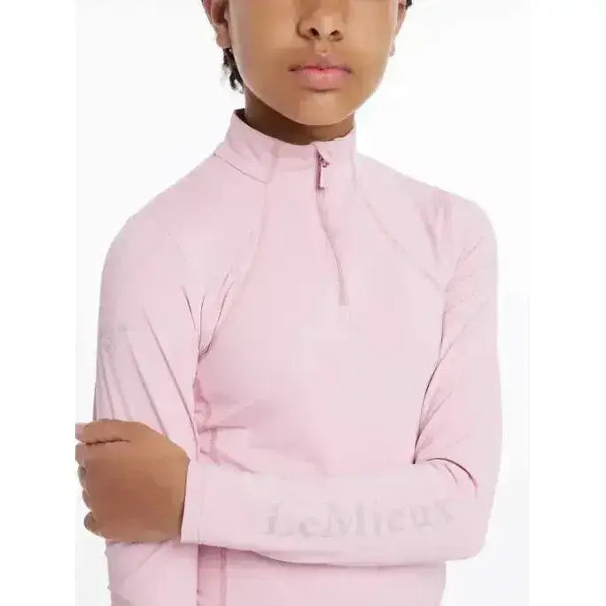 A soft pink lemieux young rider base layer blossom with long sleeves high collar and half zip closure