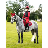 A lemieux young rider in a red rider base layer chilli outfit sits on a dapple grey horse with matching red gear