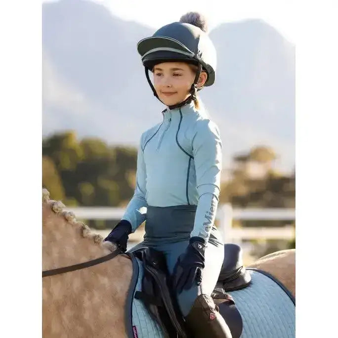 Light blue long-sleeved lemieux young rider base layer glacier with black trim and elevate branding on the sleeve