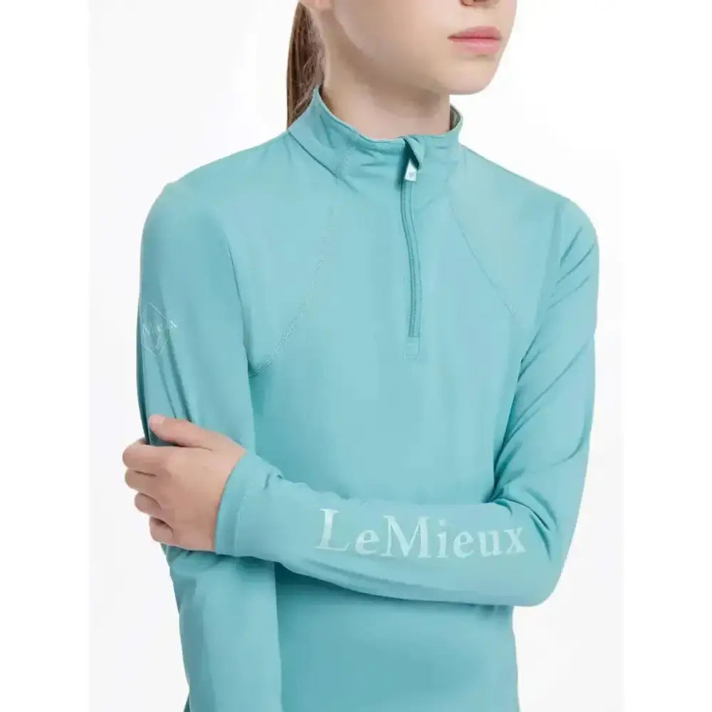 A teal lemieux young rider base layer lagoon long-sleeved performance top with quarter zip and logo on the sleeve