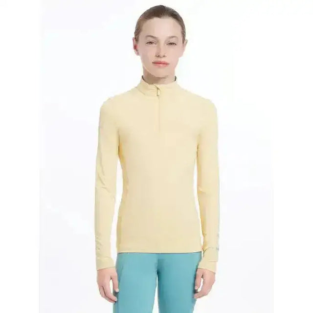 A pale yellow lemieux young rider base layer mimosa with long sleeves and a half-zip collar for performance wear