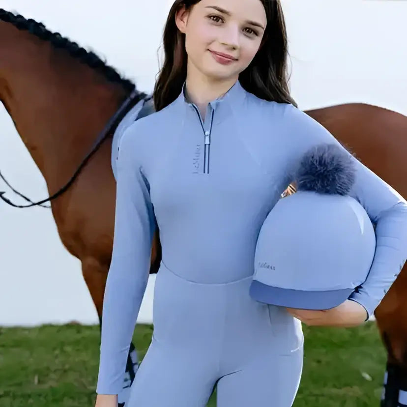 Light blue lemieux young rider equestrian helmet with fuzzy gray pom-pom for rider classique base layer powder look