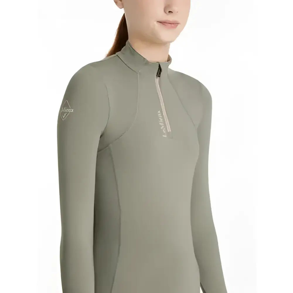 A sleek olive-green lemieux young rider classic rider rosemary base layer with long sleeves high collar and zipper detail