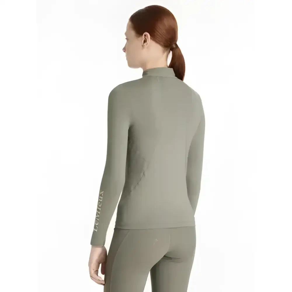 A sleek olive green lemieux young rider classic rider rosemary base layer with high collar and side seam detailing