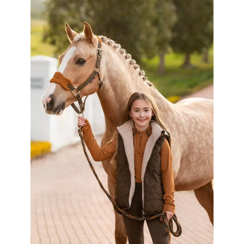 Pale horse with braided mane beside a child in Lemieux Young Rider Eloise Reversible Gilet