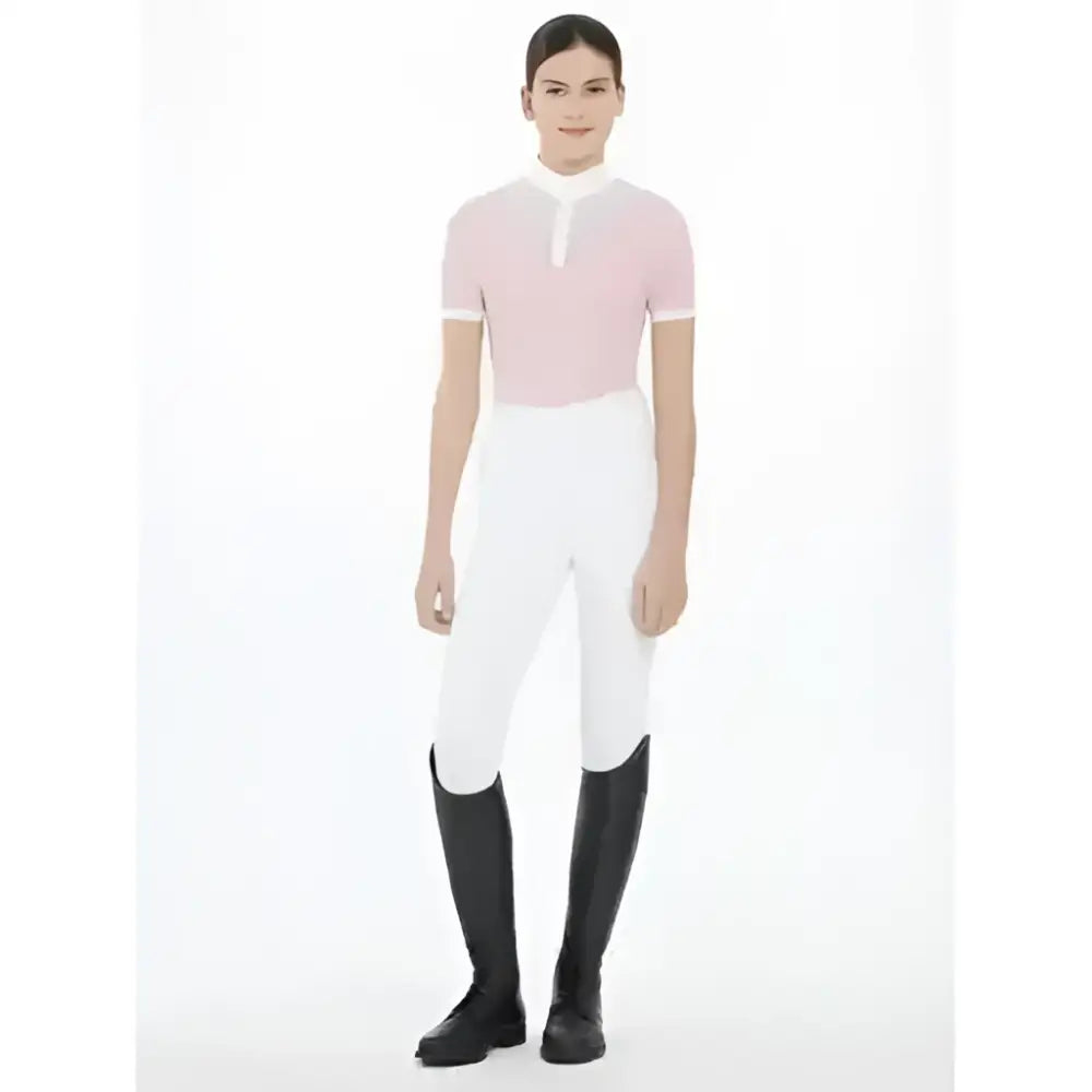 A woman wearing lemieux young rider eva short sleeve show shirt blossom in pink and white with white riding pants