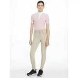 A woman wearing lemieux young rider hunter breeches beige paired with a soft pink polo shirt and white trim