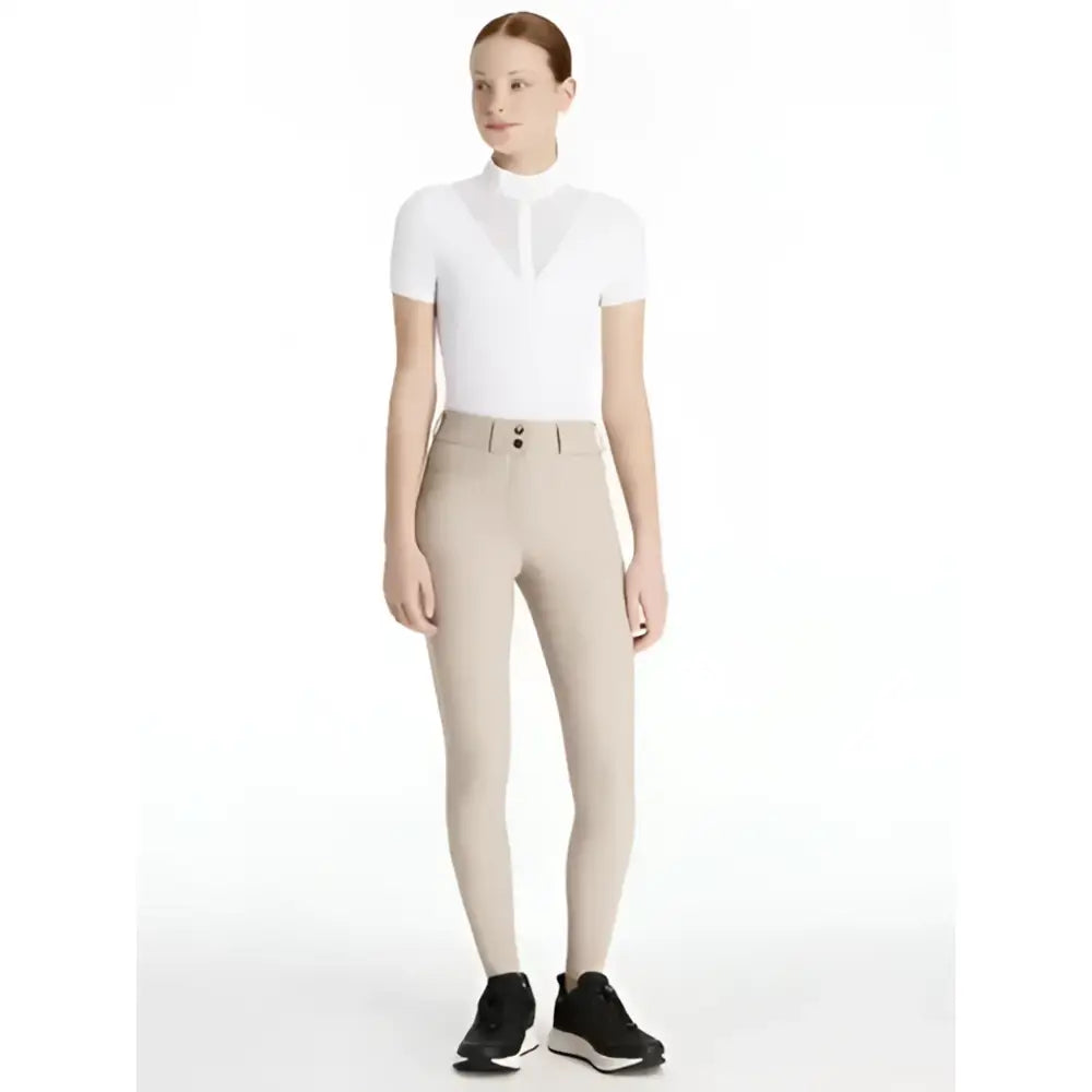 White short-sleeved lemieux young rider top with high collar paired with izzy knee grip breeches almond color