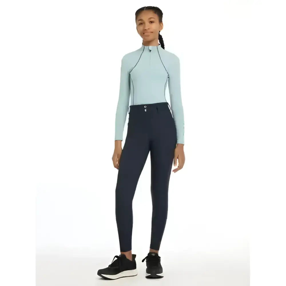 Light blue long-sleeved lemieux young rider top with high collar and zipper front for riding comfort