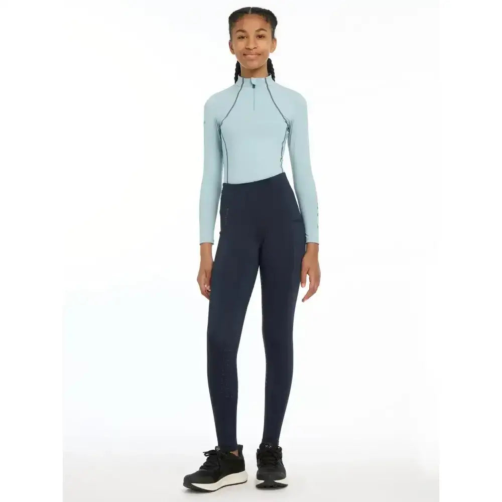 Light blue long-sleeve athletic top with black zipper paired with dark navy lemieux young rider orla pull ons leggings
