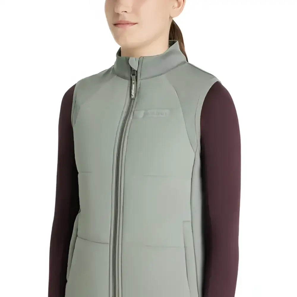 A sleek light gray quilted lemieux young rider pammy training gilet with high collar and front zipper for riding