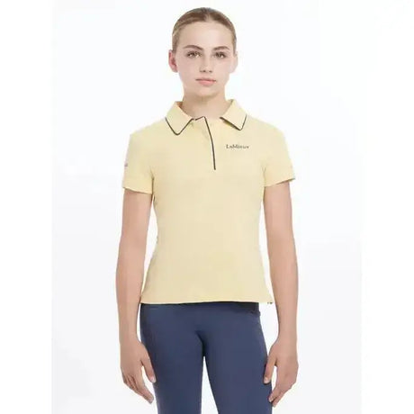 A pale yellow lemieux young rider polo shirt mimosa with black trim and subtle logo embroidery on the left chest