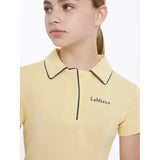 A pale yellow lemieux young rider polo shirt mimosa with black trim and subtle embroidery on the chest