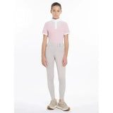 A young woman wearing lemieux young rider remi breggings stone in light gray paired with a pink polo shirt