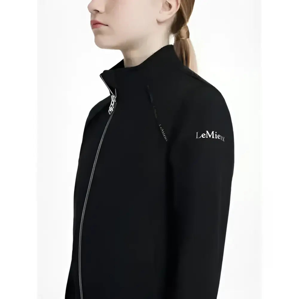 Black lemieux young rider soft shell jacket with silver zipper and subtle logo on sleeve in shell jacket black style