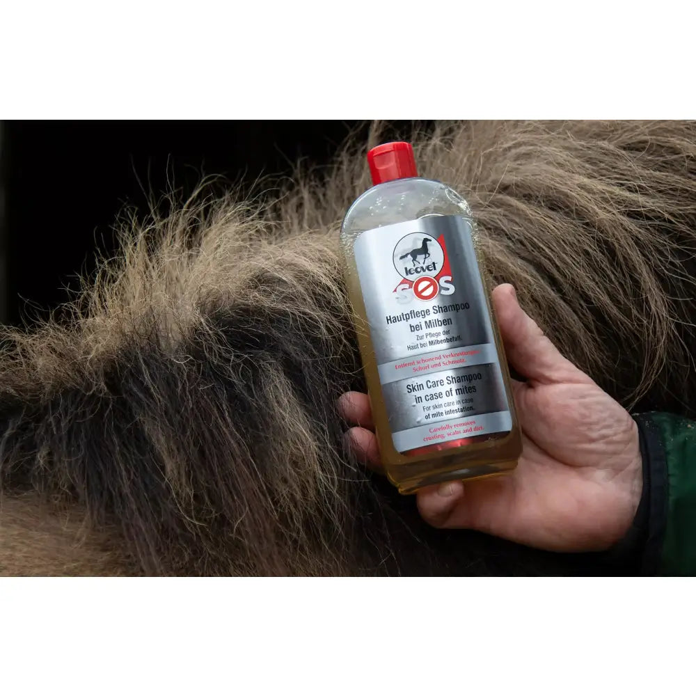 A clear plastic bottle with a red cap of leovet sos skin care shampoo held against a horse’s fur for mild irritation