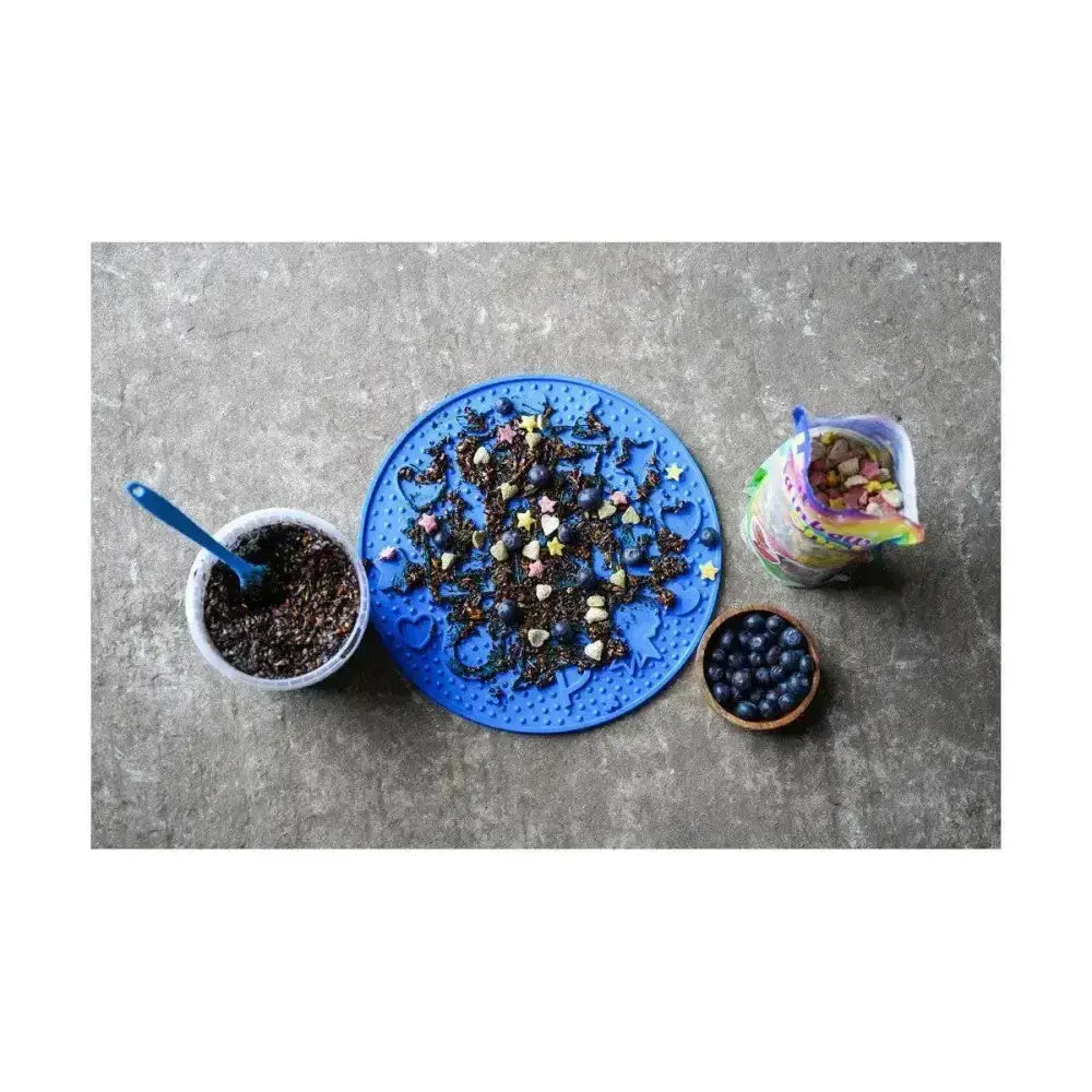 Blue silicone likit graze paste treat mat with raised patterns and scattered tasty licking paste goodies