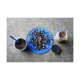 Blue silicone likit graze paste treat mat with raised patterns and scattered tasty licking paste goodies