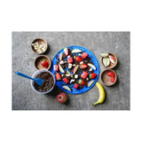 Blue silicone plate with textured surface filled with dark granola topped with fruit for likit graze paste tasty licking paste