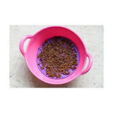 Pink plastic colander with purple silicone insert holding brown granular likit graze paste tasty licking paste