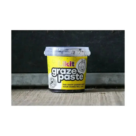 Yellow plastic tub of likit graze paste with clear lid and cartoon horse logo tasty licking paste for horses