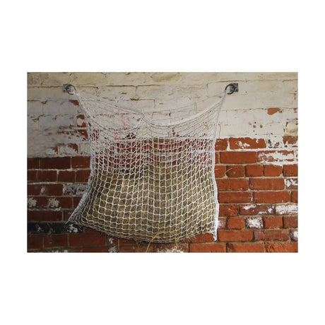White mesh hay net hanging from metal hooks on brick wall using lincoln haynet hanger for easy storage