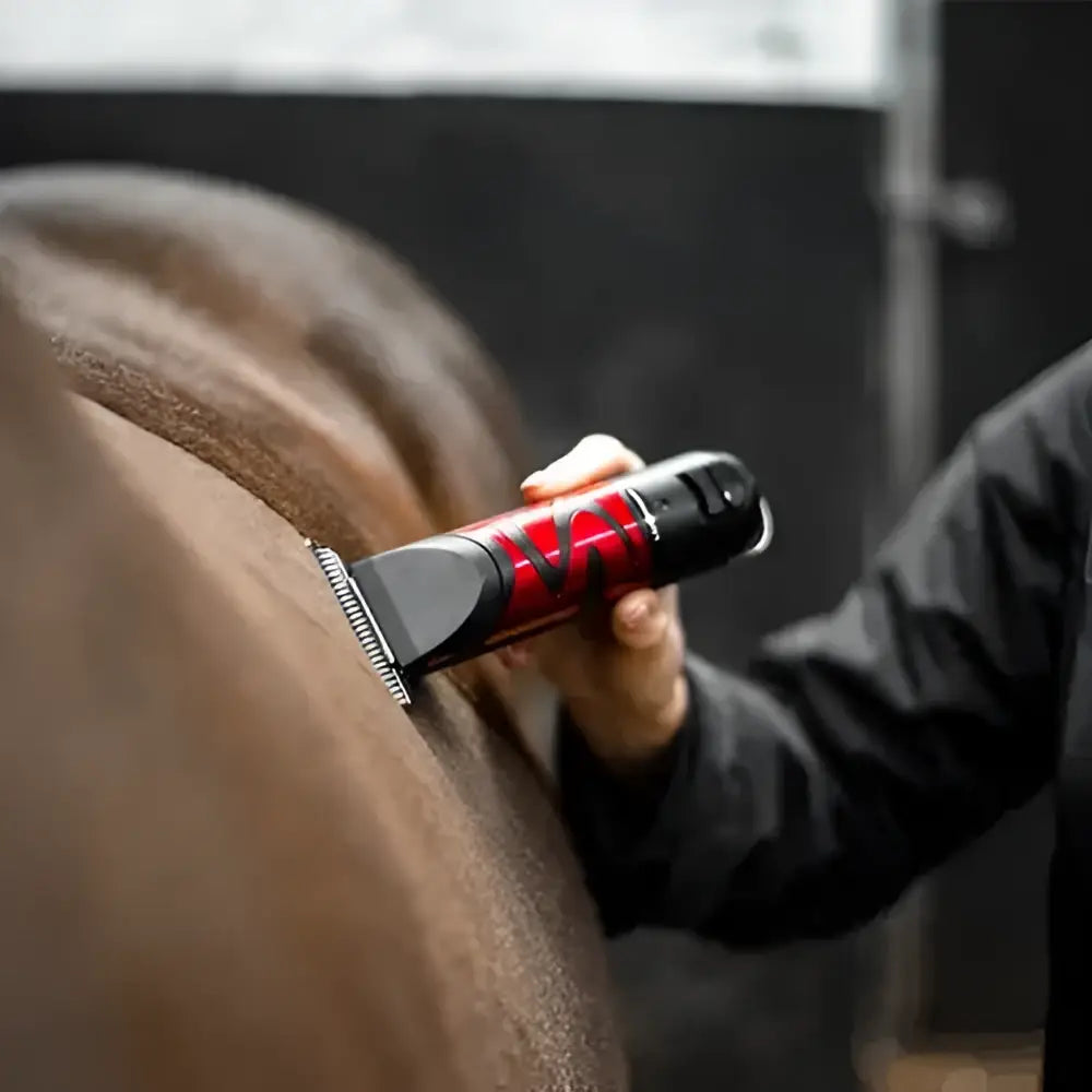 Red and black liveryman harmony plus horse clippers in use on a nervous horse for smooth trimming and comfort