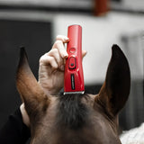 Hand holding red liveryman nova trimmer electric clipper above the back of a brown horse’s head