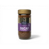 A glass jar of miles tea freeze dried instant decaf coffee with a purple label and gold lid