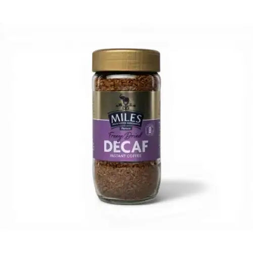 A glass jar of miles tea freeze dried instant decaf instant coffee with a purple label and gold lid