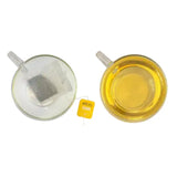A yellow miles tea lemon envelope teabag with black text and loose dark tea inside a clear plastic pouch featuring lemon verbena