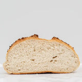 A golden-brown crusty mixed seed cob with a soft airy interior and seeds on top in a round loaf shape
