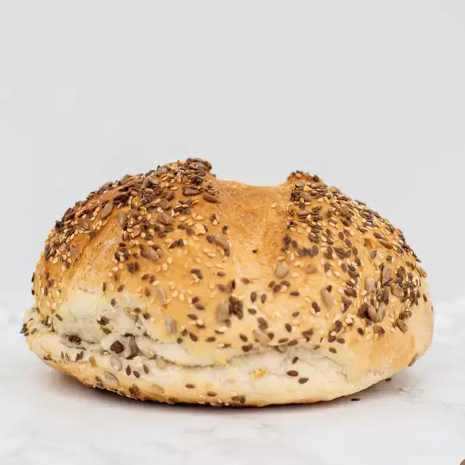 Golden brown mixed seed cob round loaf with sesame seeds and a soft slightly chewy interior perfect for sandwiches
