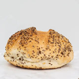 Golden brown mixed seed cob round loaf with sesame seeds and a soft slightly chewy interior perfect for sandwiches