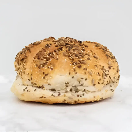 A golden-brown mixed seed cob round loaf with a soft fluffy interior and a slightly crispy crust