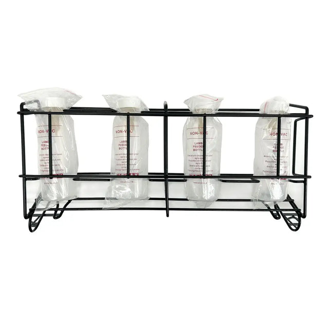Black metal rack holding four clear plastic lamb feeder bottles sealed in bags with white caps nettex agri non-vac system