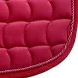 Quilted pink fabric dressage saddle pad with decorative cord trim along the edge