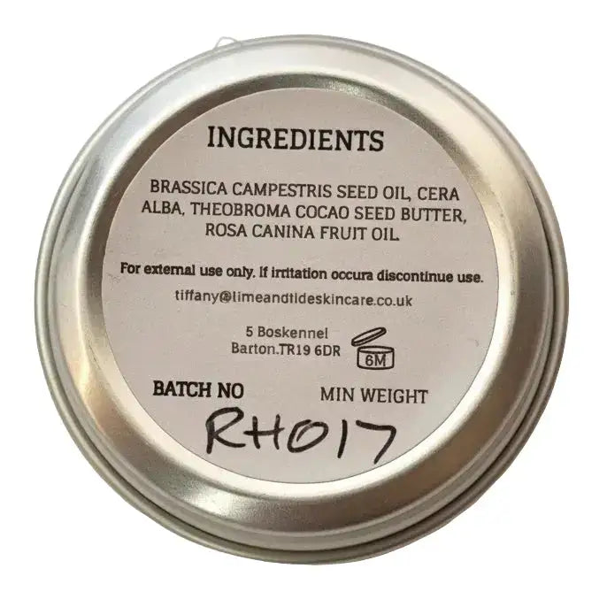 Silver metal tin showing the back label with ingredients of north devon honey luxury beeswax lip balm
