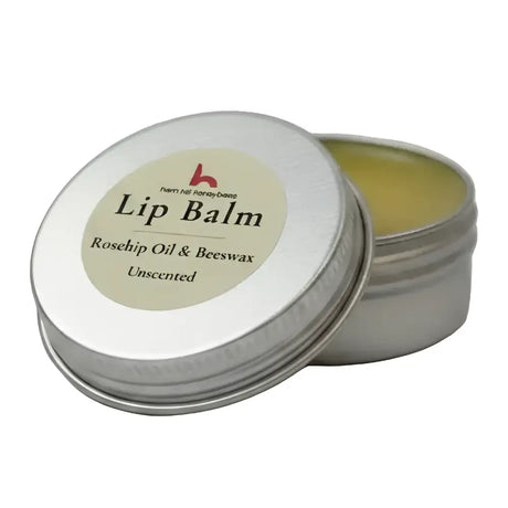 Silver tin with beige label showing ingredients for north devon honey luxury beeswax lip balm with rosehip oil