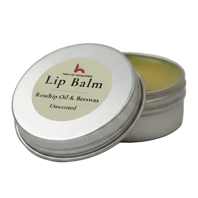 Silver tin with beige label showing ingredients for north devon honey luxury beeswax lip balm with rosehip oil
