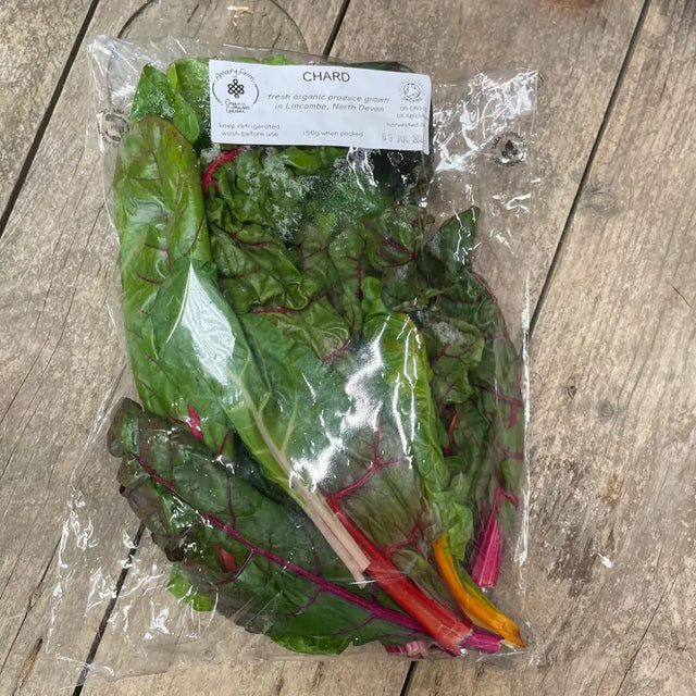 A fresh package of hand grown organic chard with vibrant green leaves and colorful red pink and orange stems
