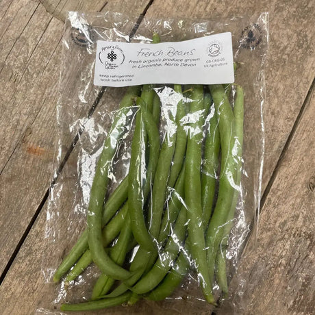 A clear plastic pack of fresh green organic french beans from a farm in north devon labeled organic french beans
