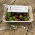 A clear plastic container of organic gooseberries in green and deep red with an organic farm sticker