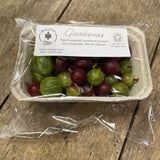 A clear plastic container of organic gooseberries in green and deep red with an organic farm sticker