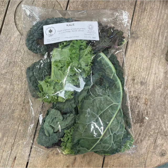 A package of fresh organic kale with dark green curly leaves and a white label from a certified farm equestrian quality