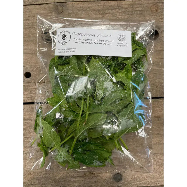 A clear plastic bag filled with fresh vibrant green organic mint leaves from an organically certified farm