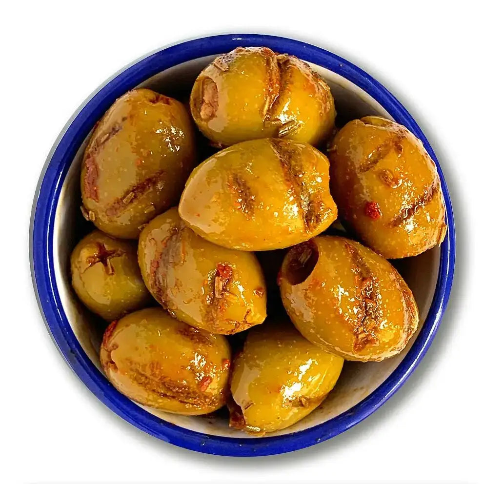 A bowl of glossy organic smoky paprika and rosemary grilled olives with golden green color and charred red pepper flakes