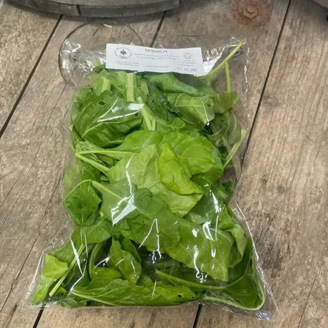 A clear plastic bag of fresh organic spinach leaves with a white label perfect for equestrian horse diets