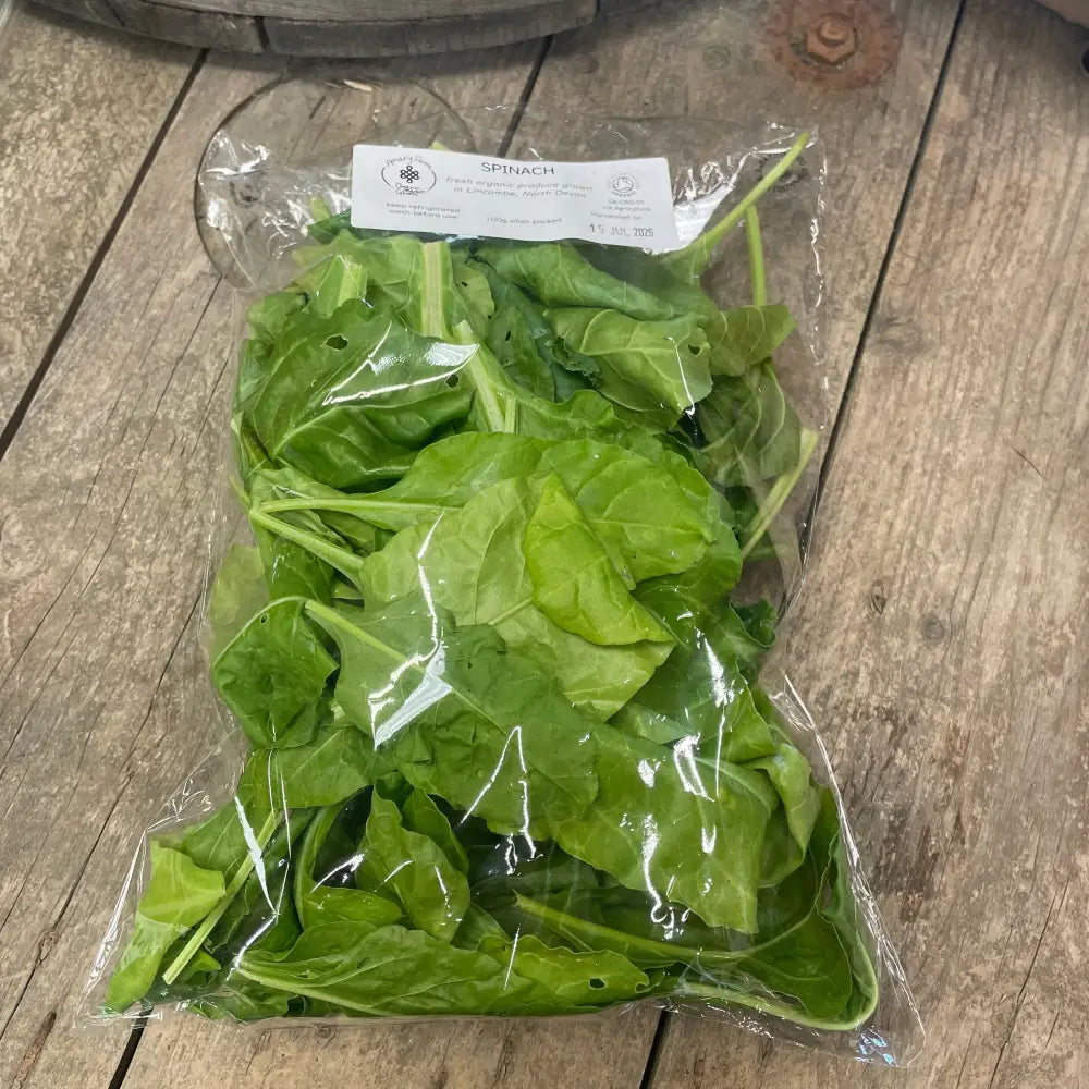 A clear plastic bag of fresh organic spinach leaves with a white label perfect for equestrian horse diets